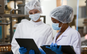 Two women in lab coats reviewing documents