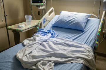 Hospital bed and pillow with glowing contamination spots under ultraviolet light