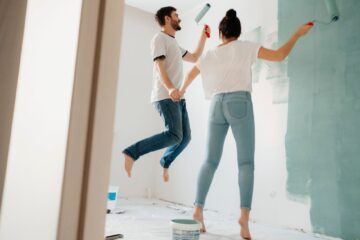 Applying antimicrobial paint for home walls — couple painting a bedroom wall